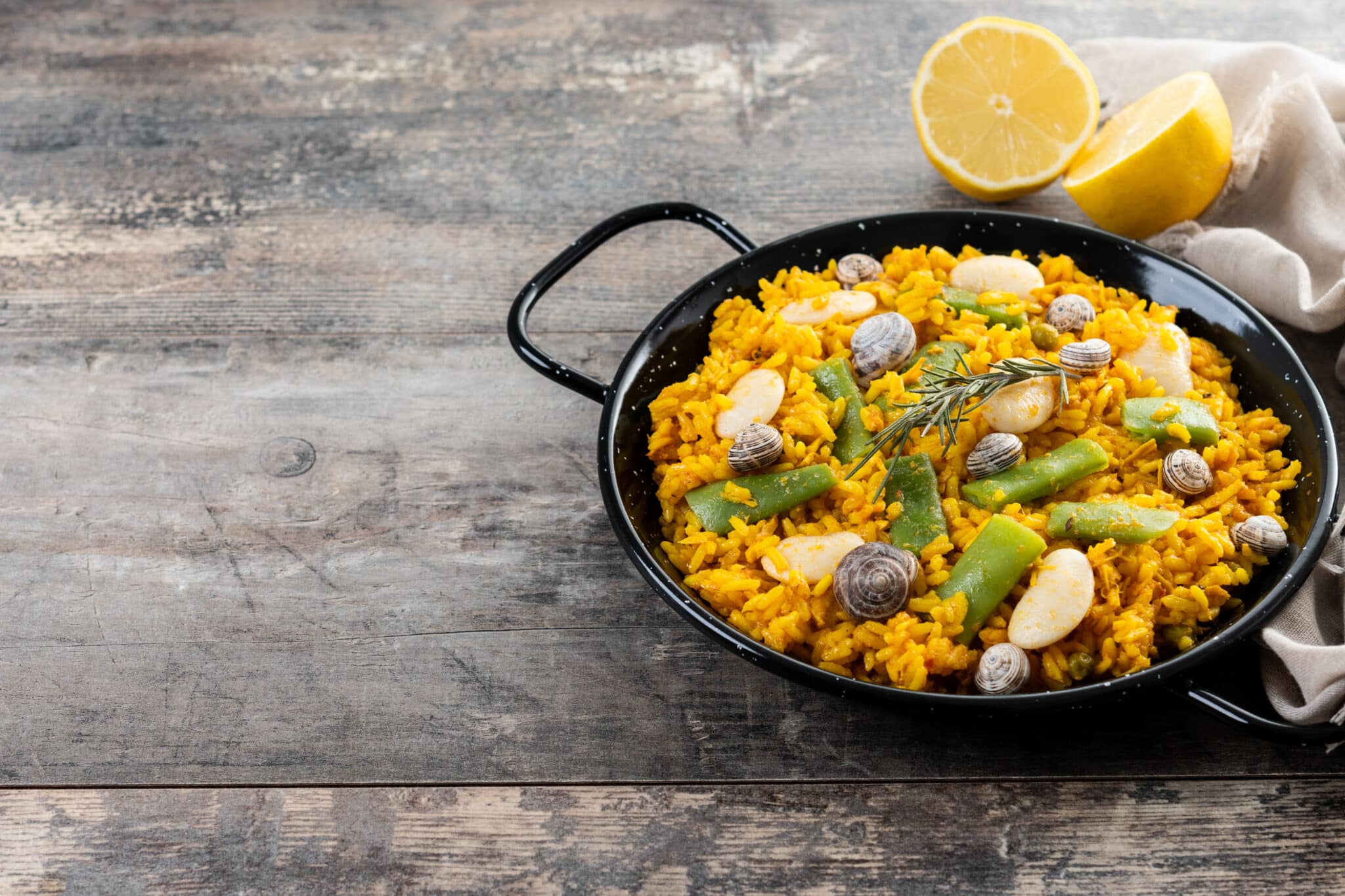 Traditional Valencian paella with rabbit, chicken, garrofon beans, snails, Moroccan green beans and saffron on wooden table