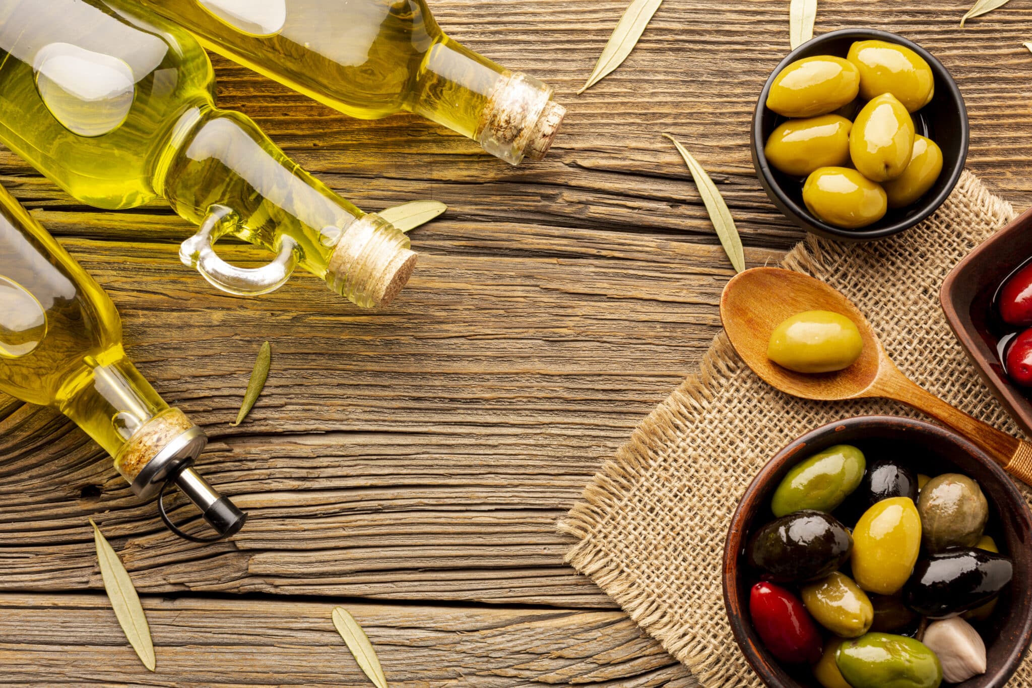 flat-lay-olives-bowls-oil-bottles-leaves-textile-material